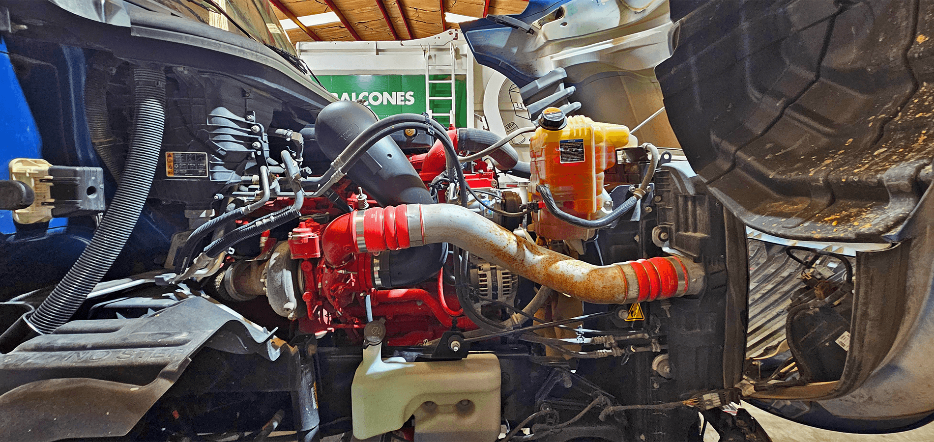 Semi-truck engine bay with coolant reservoir and cooling system hoses at Salazar Semi-Truck Repair in Dallas TX